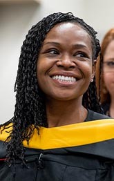 A graduating student smiles about connecting with fellow alumni